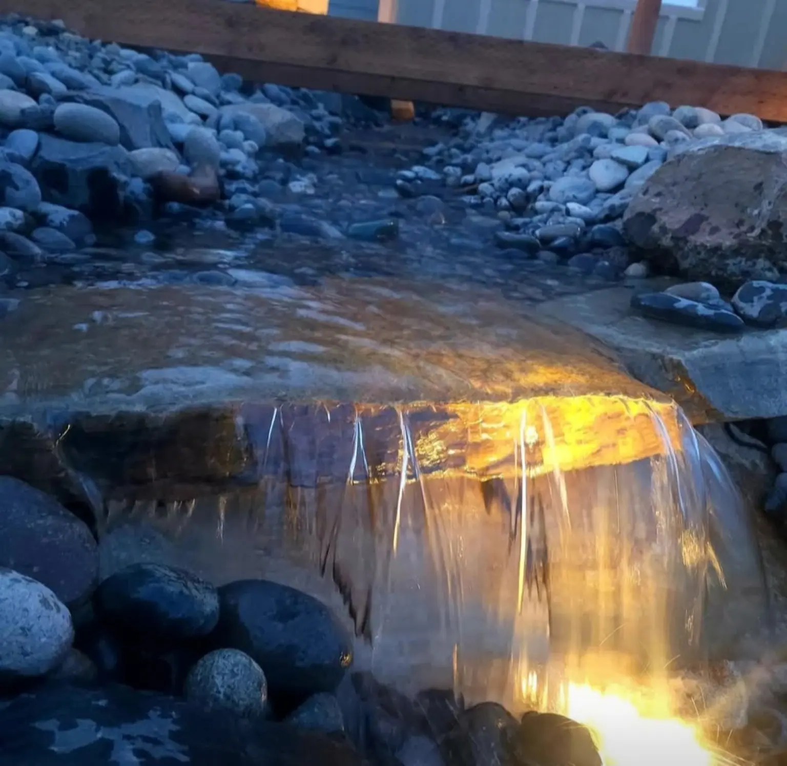 Lit stream with a waterfall over river rock